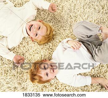 Stock Image - two young brothers 
lie side by side 
on a carpet, laughing. 
fotosearch - search 
stock photos, 
pictures, images, 
and photo clipart