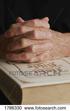 Stock Photography - senior's folded 
hands on holy 
bible. fotosearch 
- search stock 
photos, pictures, 
images, and photo 
clipart
