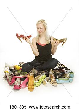 Stock Image - woman sitting 
in pile of shoes 
while holding 
two high heeled 
shoes. fotosearch 
- search stock 
photos, pictures, 
images, and photo 
clipart
