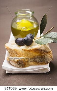 Stock Photograph - olive sprig with 
black olives on 
white bread, olive 
oil behind. fotosearch 
- search stock 
photos, pictures, 
images, and photo 
clipart