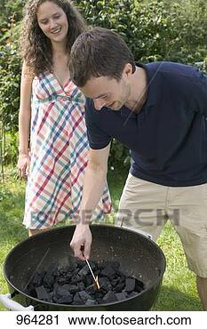 Stock Photography - couple having 
barbecue in garden 
(man lighting 
charcoal). fotosearch 
- search stock 
photos, pictures, 
images, and photo 
clipart