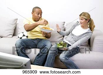Stock Photograph - couple with peanut 
puffs and salad 
in front of tv. 
fotosearch - search 
stock photos, 
pictures, images, 
and photo clipart