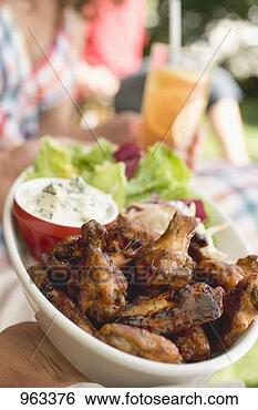 Stock Photo - hands holding 
chicken wings 
with salad, people 
in background. 
fotosearch - search 
stock photos, 
pictures, images, 
and photo clipart