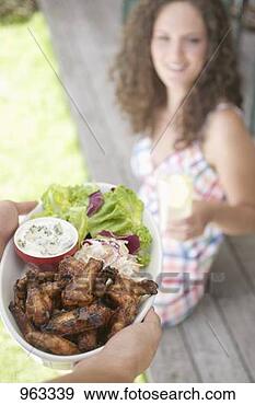 Stock Photograph - hands serving 
grilled chicken 
wings, woman in 
background. fotosearch 
- search stock 
photos, pictures, 
images, and photo 
clipart