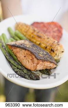 Stock Photography - person holding 
plate of grilled 
salmon, corn on 
the cob, vegetables. 
fotosearch - search 
stock photos, 
pictures, images, 
and photo clipart