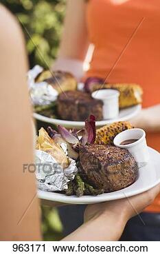 Stock Photography - two women holding 
plates of grilled 
steak & accompaniments. 
fotosearch - search 
stock photos, 
pictures, images, 
and photo clipart