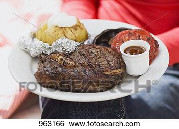 Stock Photo - woman holding 
plate of steak, 
baked potato, 
vegetables & sauce. 
fotosearch - search 
stock photos, 
pictures, images, 
and photo clipart