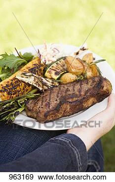 Stock Photograph - woman holding 
plate of steak, 
grilled vegetables 
& corn on the 
cob. fotosearch 
- search stock 
photos, pictures, 
images, and photo 
clipart