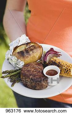 Stock Photo - woman holding 
a plate of grilled 
steak and accompaniments. 
fotosearch - search 
stock photos, 
pictures, images, 
and photo clipart