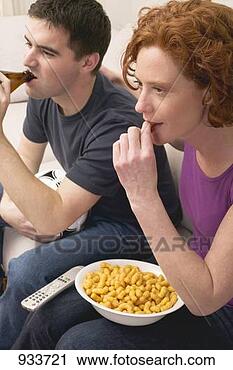 Stock Photography - young couple with 
football, beer 
and snack food 
watching tv. fotosearch 
- search stock 
photos, pictures, 
images, and photo 
clipart