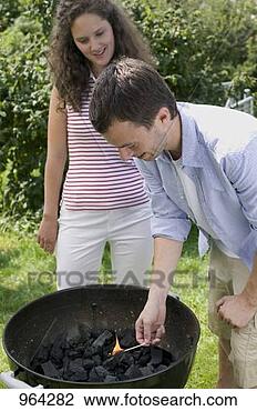Stock Photo - couple having 
barbecue in garden 
(man lighting 
charcoal). fotosearch 
- search stock 
photos, pictures, 
images, and photo 
clipart