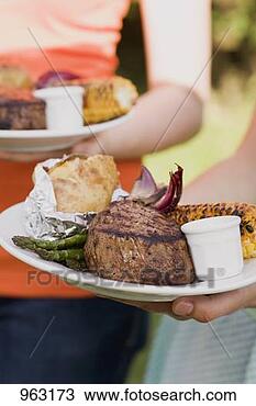 Stock Photo - two women holding 
plates of grilled 
steak & accompaniments. 
fotosearch - search 
stock photos, 
pictures, images, 
and photo clipart
