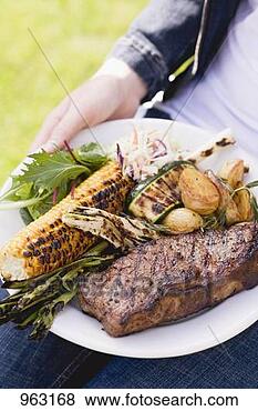 Stock Photo - woman holding 
plate of steak, 
grilled vegetables 
& corn on the 
cob. fotosearch 
- search stock 
photos, pictures, 
images, and photo 
clipart