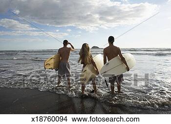 Stock Photo - three friends 
walking into surf, 
holding surf boards, 
rear view. fotosearch 
- search stock 
photos, pictures, 
images, and photo 
clipart