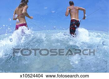 Stock Photo - couple running 
in surf, low angle 
view, rear view 
(wide-angle). 
fotosearch - search 
stock photos, 
pictures, images, 
and photo clipart