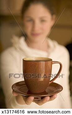 Stock Photo - young woman holding 
coffee cup (focus 
on coffee cup 
in foreground). 
fotosearch - search 
stock photos, 
pictures, images, 
and photo clipart