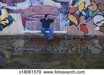 Stock Photograph - spain, seville, 
man sitting on 
bench by graffiti 
on wall. fotosearch 
- search stock 
photos, pictures, 
images, and photo 
clipart