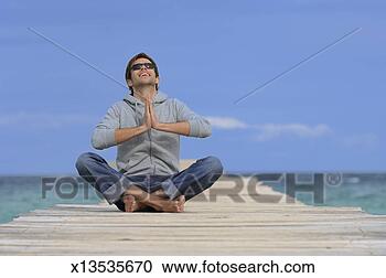 Stock Photography - man sitting in 
prayer position 
on jetty. fotosearch 
- search stock 
photos, pictures, 
images, and photo 
clipart