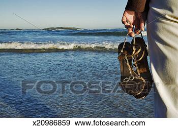 Stock Photograph - mature woman at 
seashore, holding 
sandals, mid section, 
rear view. fotosearch 
- search stock 
photos, pictures, 
images, and photo 
clipart