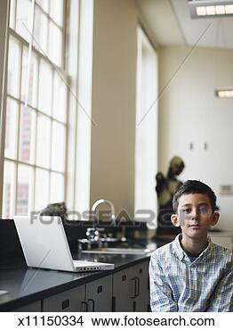 Stock Photo - boy (6-7) sitting 
next to laptop 
science lab, portrait. 
fotosearch - search 
stock photos, 
pictures, images, 
and photo clipart