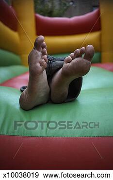 Stock Photograph - boy (13-14) with 
dirty feet lying 
in bouncy castle, 
close-up of feet. 
fotosearch - search 
stock photos, 
pictures, images, 
and photo clipart