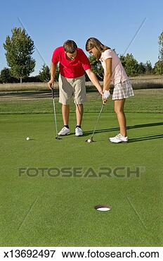 Picture - golf instructor 
teaching young 
female student 
(13-14) putting 
on golf. fotosearch 
- search stock 
photos, pictures, 
images, and photo 
clipart