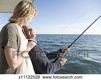 Stock Photo - mature couple 
on watercraft, 
man fishing. fotosearch 
- search stock 
photos, pictures, 
images, and photo 
clipart