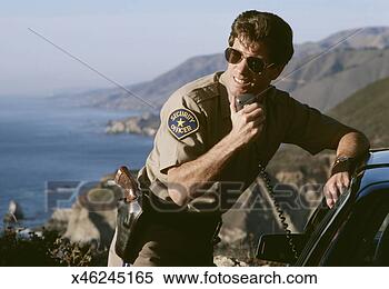 Stock Image - police man using 
car radio near 
coastal cliffs. 
fotosearch - search 
stock photos, 
pictures, images, 
and photo clipart