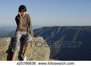 Stock Photo - teenage girl (13-14) 
in mountains, 
 sitting on boulder, 
 talking on. fotosearch 
- search stock 
photos, pictures, 
images, and photo 
clipart