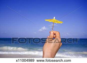 Stock Photograph - woman holding 
small drink umbrella 
against sea, close-up 
of hand. fotosearch 
- search stock 
photos, pictures, 
images, and photo 
clipart