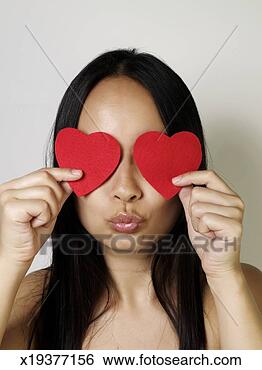 Stock Photo - young woman puckering, 
holding two felt 
hearts over eyes. 
fotosearch - search 
stock photos, 
pictures, images, 
and photo clipart