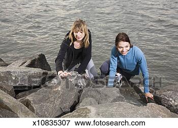 Picture - usa,  new york, 
 brooklyn,  dumbo, 
 two women climbing 
over rocks by. 
fotosearch - search 
stock photos, 
pictures, images, 
and photo clipart