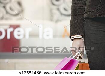 Stock Photo - woman holding 
shopping bags 
standing on street, 
mid section, close 
up. fotosearch 
- search stock 
photos, pictures, 
images, and photo 
clipart