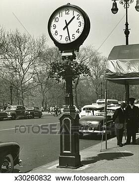Stock Photo - decorative street 
clock,  two background 
people standing 
on street. fotosearch 
- search stock 
photos, pictures, 
images, and photo 
clipart