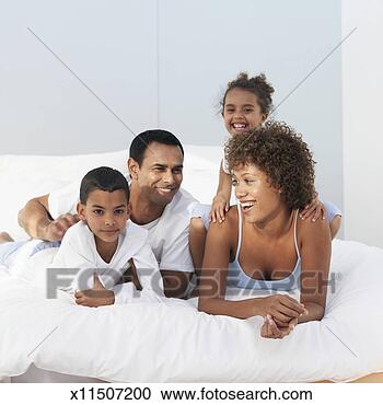 Stock Photography - parents with daughter 
(4-5 years) and 
son (6-7 years) 
lying on bed. 
fotosearch - search 
stock photos, 
pictures, images, 
and photo clipart