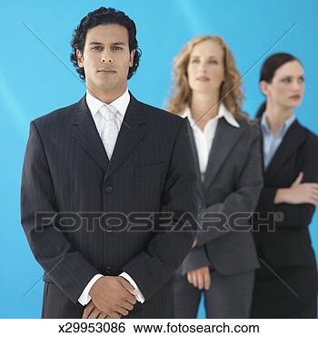 Stock Photo - young business 
man looking at 
camera, two business 
women in background. 
fotosearch - search 
stock photos, 
pictures, images, 
and photo clipart