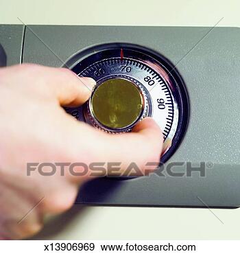 Stock Photograph - elevated view 
of man's hand 
turning combination 
lock of safe. 
fotosearch - search 
stock photos, 
pictures, images, 
and photo clipart