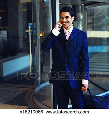 Stock Photo - front view of 
businessman walking 
carrying luggage 
case and talking. 
fotosearch - search 
stock photos, 
pictures, images, 
and photo clipart
