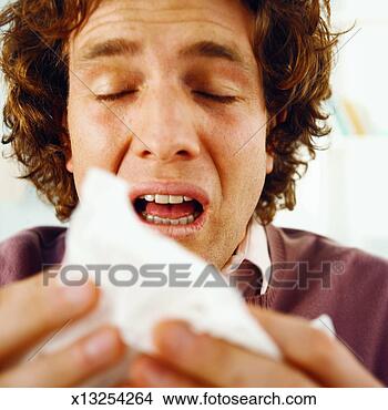 Stock Photo - close-up of mid 
adult man sneezing 
into tissue. fotosearch 
- search stock 
photos, pictures, 
images, and photo 
clipart