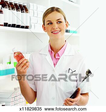 Stock Image - front view of 
pharmacist holding 
clip-board and 
examining container. 
fotosearch - search 
stock photos, 
pictures, images, 
and photo clipart