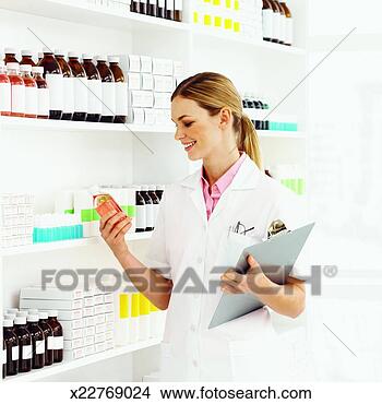 Stock Photo - side view of pharmacist 
holding clip-board 
and examining 
container of. 
fotosearch - search 
stock photos, 
pictures, images, 
and photo clipart