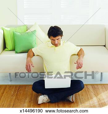 Stock Photography - front view of 
mid adult man 
sitting on floor 
working on laptop. 
fotosearch - search 
stock photos, 
pictures, images, 
and photo clipart