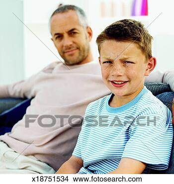 Stock Photo - front view portrait 
of father and 
son sitting on 
sofa (10-11). 
fotosearch - search 
stock photos, 
pictures, images, 
and photo clipart