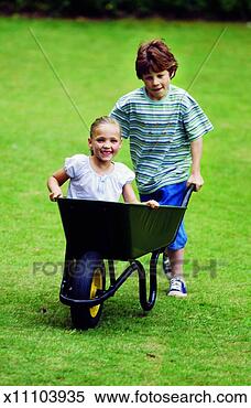 Stock Image - boy (10-11) pushing 
girl (8-9) in 
a wheelbarrow. 
fotosearch - search 
stock photos, 
pictures, images, 
and photo clipart