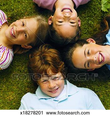 Stock Photography - close-up of four 
children lying 
on grass with 
heads together 
(8-12). fotosearch 
- search stock 
photos, pictures, 
images, and photo 
clipart