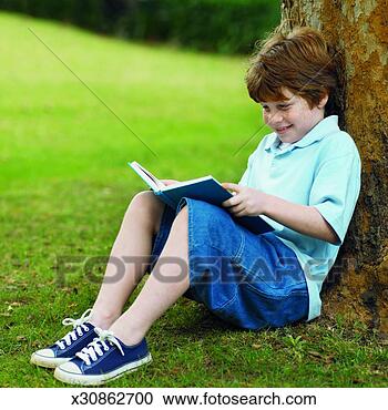 Stock Photography - side view of boy 
sitting under 
tree in garden 
reading book (10-11). 
fotosearch - search 
stock photos, 
pictures, images, 
and photo clipart