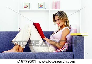 Stock Photography - side view of young 
woman sitting 
on sofa and reading 
book. fotosearch 
- search stock 
photos, pictures, 
images, and photo 
clipart