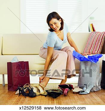 Stock Photo - young woman sitting 
on sofa trying 
on new shoes. 
fotosearch - search 
stock photos, 
pictures, images, 
and photo clipart