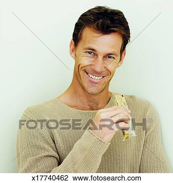 Stock Photo - front view of 
mid adult man 
holding cereal 
bar. fotosearch 
- search stock 
photos, pictures, 
images, and photo 
clipart