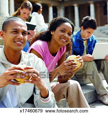 Stock Photograph - close-up of young 
people sitting 
outside college 
eating and working. 
fotosearch - search 
stock photos, 
pictures, images, 
and photo clipart
